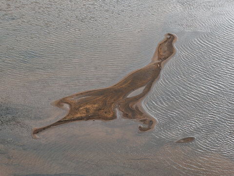 Aerial view of a sandbar in the water with intricate patterns formed by tidal currents in Unalaska, Alaska, United States.