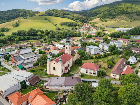 Aerial view of the historic church and residential buildings nestled among green hills in Kokava nad Rimavicou, Banska Bystrica Region, Slovakia.