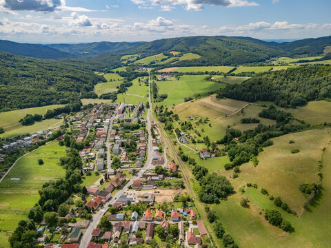 Aerial view of the town nestled in a valley surrounded by rolling green hills, forests, and agricultural fields in Kokava nad Rimavicou, Banska Bystrica Region, Slovakia.