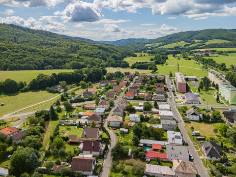 Aerial view of the village of Kokava nad Rimavicou nestled in a lush green valley surrounded by rolling hills and forests in Kokava nad Rimavicou, Banska Bystrica Regio, Slovakia.