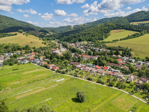 Aerial view of the village of Kokava nad Rimavicou nestled among rolling green hills and meadows in Kokava nad Rimavicou, Banska Bystrica Regio, Slovakia.