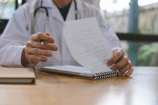 Doctor reviewing medical notes and patient records at a desk with stethoscope, representing healthcare documentation, clinical assessment, diagnosis, consultation and professional medical care.