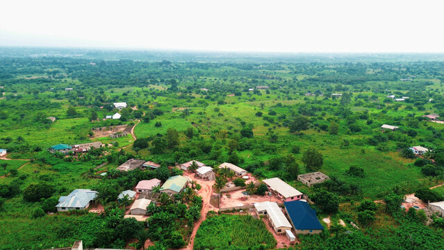 Aerial view of Wli village surrounded by lush green vegetation, scattered houses, and dirt paths in the rural landscape of Wli, Volta Region, Ghana.