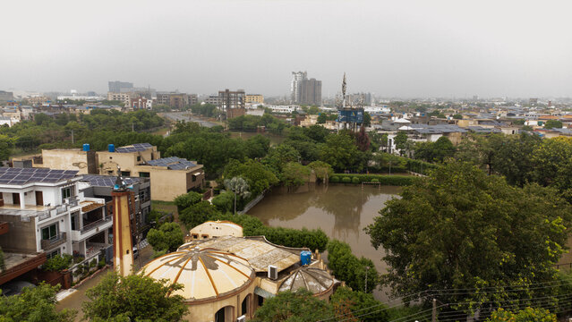 Aerial view of PCSIR Phase 2 featuring residential houses with solar panels, a mosque with a dome, and a flooded park area in Lahore, Punjab, Pakistan.