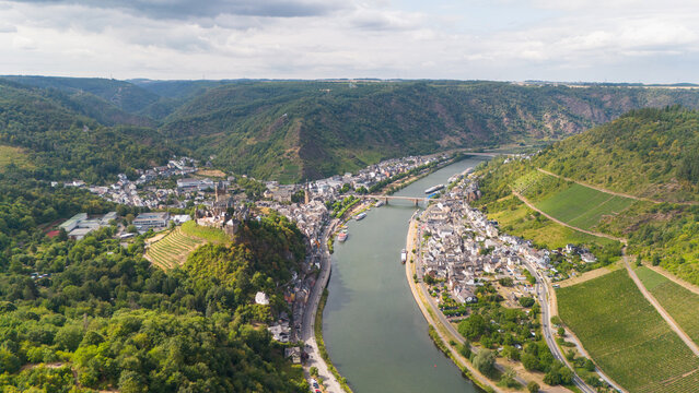 Aerial view of Reichsburg Cochem castle on a hilltop overlooking the Moselle river valley, surrounded by vineyards, forests, and the historic town of Cochem, Rhineland-Palatinate, Germany.