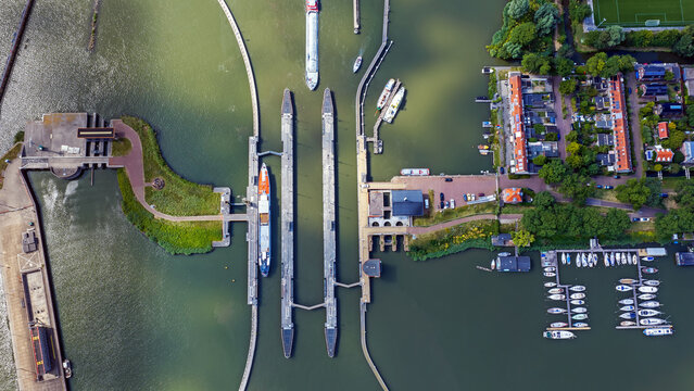 Aerial view of the Oranjesluizen canal locks with boats navigating the waterway, surrounded by lush green banks and residential buildings in Amsterdam, Noord-Holland, Netherlands.