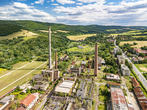 Aerial view of the abandoned Former Slovak Chemical Works factory with tall brick chimneys, derelict industrial buildings, and overgrown vegetation in Hnusta, Banska Bystrica Regio, Slovakia.
