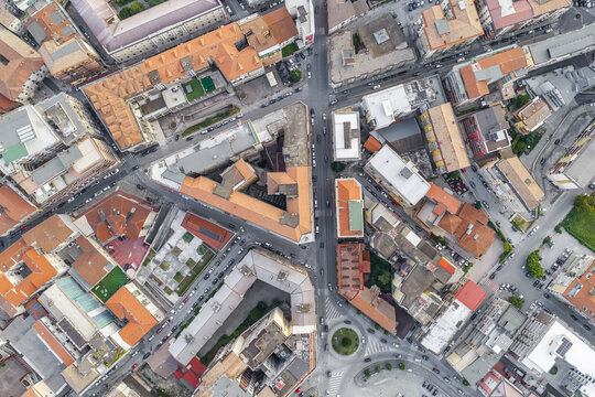 Aerial view of the urban layout of Avellino, featuring dense residential buildings with terracotta rooftops, intersecting streets, and a small roundabout, Avellino, Campania, Italy.