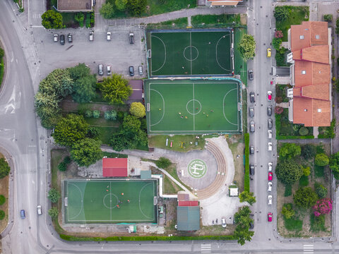 Aerial view of a sports complex featuring three green soccer fields, an outdoor amphitheater, and surrounding trees in Avellino, Campania, Italy.
