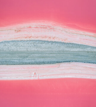Aerial view of abstract pink salt pond with layered mineral formations in the Camargue region of France.