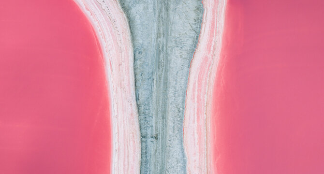 Aerial view of pink salt ponds separated by a central service road in the Camargue, France.