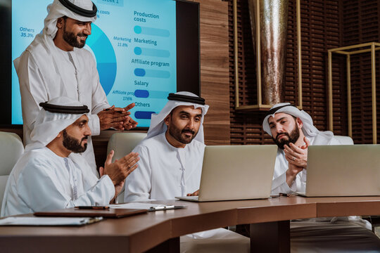 Arab businessmen collaborating on laptop during office meeting