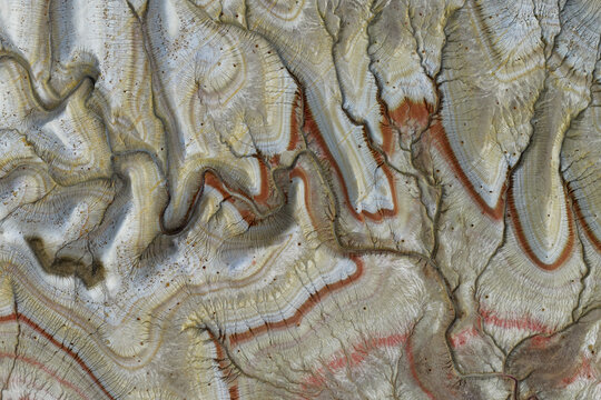 Aerial view of geological rock formations with intricate layered patterns and red sediment erosion in the landscape of Kazakhstan.