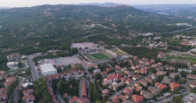 Aerial view of the Stadio Partenio-Adriano Lombardi stadium surrounded by residential buildings, lush green hills, and roads in Avellino, Campania, Italy.