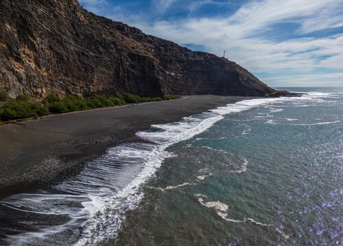 Aerial view of the black sand beach of Tarrafal de Monte Trigo, nestled against the dramatic cliffs of Santo Antao, with waves crashing in Tarrafal de Monte Trigo, Porto Novo, Cabo Verde.