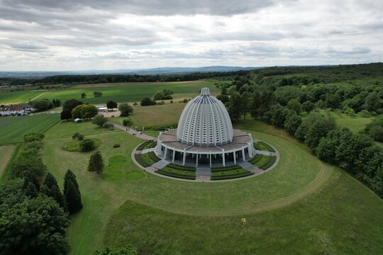 Aerial view of the Bahai House of Worship surrounded by lush green fields, trees, and landscaped gardens in Hofheim am Taunus, Hessen, Germany.