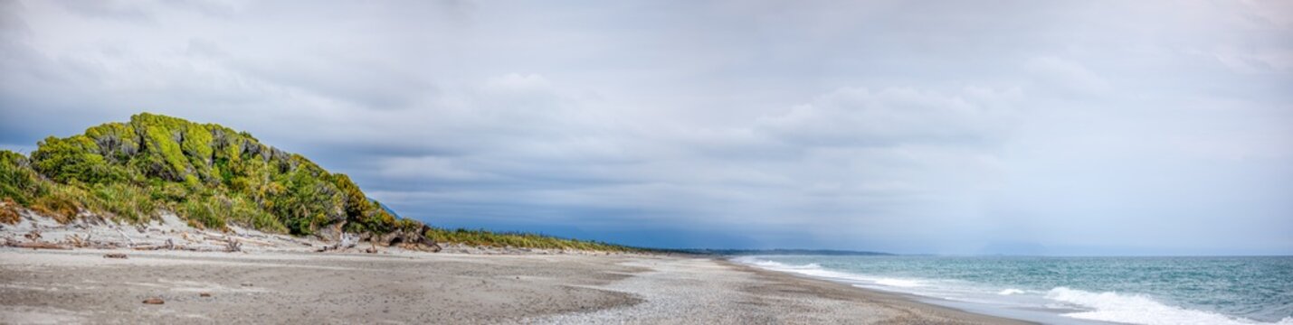 Extremes Weitwinkelpanorama am Strand von Ship Creek, endlose Sandkueste an der Tasmansee mit bewaldeter Duene, Wellen und fernen Bergsilhouetten, Westcoast, Suedinsel, Neuseeland