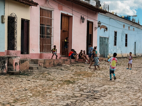 Cuba - 20 December 2024: View of children playing on a cobblestone street in front of colorful colonial-style houses.