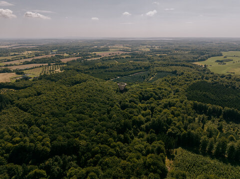Aerial view of the iconic Camp Adventure Forest Tower rising above the dense green canopy of the Gisselfeld Klosters Skove forest in Ronnede, Denmark.