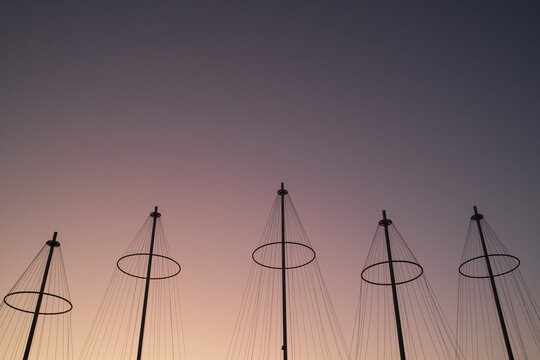 View of the sculptural masts of the Cirkelbroen bridge silhouetted against a vibrant sunset sky in Copenhagen, Denmark.
