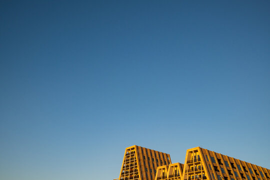 View of modern residential architecture with geometric facades and balconies under a clear blue sky in Copenhagen, Denmark.