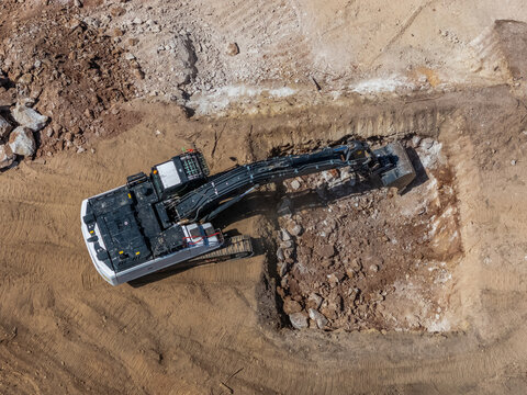 Aerial view of an excavator digging into rocky soil at a construction site in Cascais, Lisboa, Portugal.