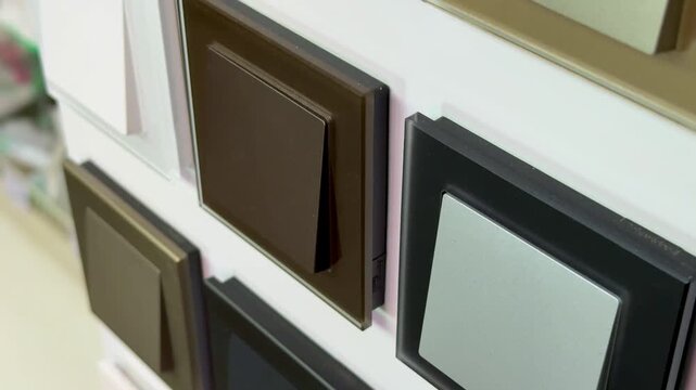 Close-up colorful electrical switches on display showcasing sample board with multiple finishes and colors glossy black, matte