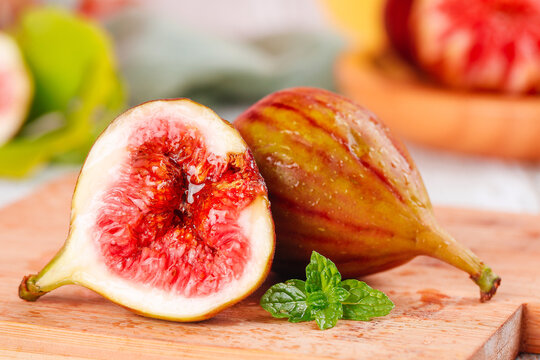 Fresh Yunnan Figs with Red Flesh Cut in Half on Wooden Board with Mint Leaves