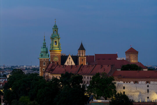 Aerial view of Wawel Castle with its historic towers and red-tiled roofs illuminated at dusk in Krakow, Lesser Poland Voivode, Poland.