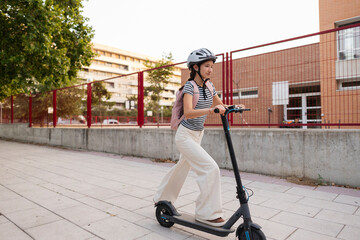 Young woman commuting on electric scooter to school © PintoArt