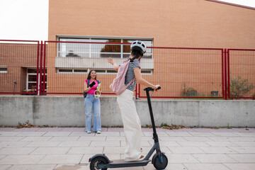 Young women friends commuting to school with electric scooter © PintoArt