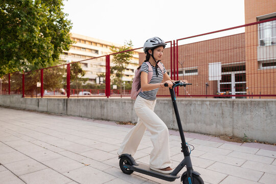 Young woman commuting on electric scooter to school