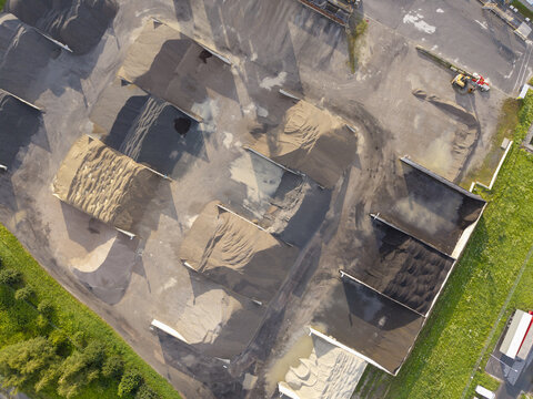 Aerial view of the asphalt plant with large piles of gravel and bitumen materials stored in open bays at the industrial site in Skawina, Lesser Poland Voivode, Poland.