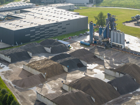 Aerial view of the bituminous mass plant featuring piles of gravel and asphalt stored in concrete bays next to an industrial warehouse in Skawina, Lesser Poland Voivode, Poland.
