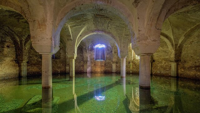 View of the flooded crypt of the Basilica of Saint Francis with ancient stone columns and arches reflecting in the clear water in Ravenna, Emilia-Romagna, Italy.