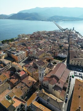 Aerial view of the historic town of Orbetello with its characteristic rooftops, narrow streets, and the long causeway stretching into the lagoon in Orbetello, Tuscany, Italy.