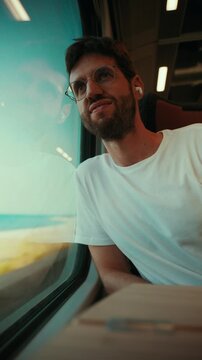 Man listens to music with wireless earbuds while traveling by train