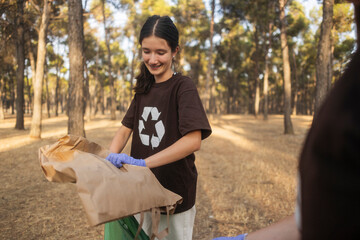 Fototapeta premium Young person collecting trash during outdoor cleanup volunteering