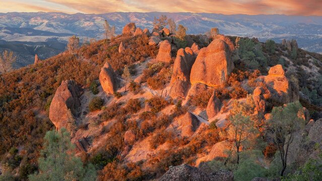 View of the rugged rock formations and volcanic spires along the High Peaks Trail at sunset, with golden light illuminating the landscape in San Benito County, California, United States.