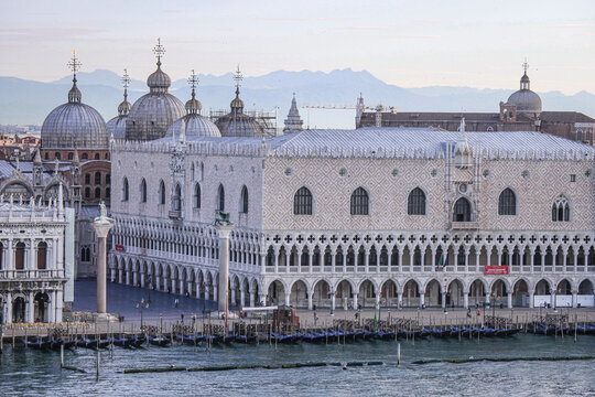 Aerial view of the Doge's Palace and St. Mark's Basilica with ornate Gothic architecture, domes, and gondolas moored along the waterfront in Venice, Veneto, Italy.