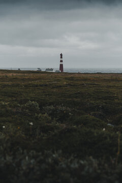 Gamvik, Finnmark, Norway - 26 August 2025: View of Slettnes Lighthouse standing on the rocky coastline under a moody overcast sky.