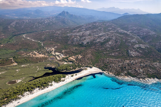 Aerial view of Plage de Saleccia with its turquoise waters, white sand beach, and surrounding rugged mountains in Corsica, France.