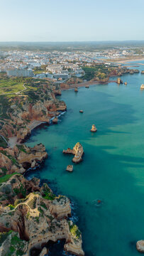 Aerial view of the dramatic limestone cliffs and turquoise waters of the Atlantic Ocean along the coastline of Lagos, Faro District, Portugal.