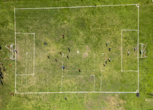 Aerial view of a soccer field with players in action on the green grass pitch in Izamal, Yucatan, Mexico.