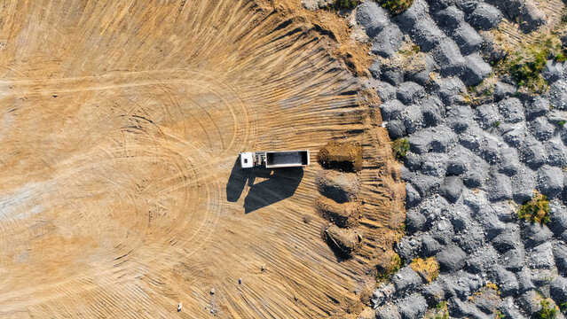 Aerial view of a dump truck parked in a quarry with piles of gravel and tire tracks in the dirt in Beocin, Vojvodina, Serbia.