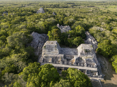 Aerial view of the ancient Maya archaeological site of Becan, featuring stone pyramids and structures surrounded by dense jungle canopy in Calakmul, Campeche, Mexico.