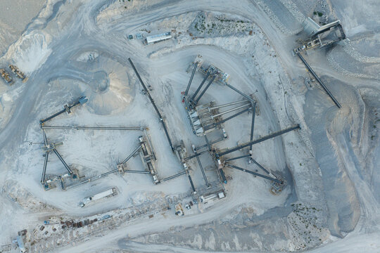 Aerial view of an industrial quarry site featuring complex conveyor belt systems and piles of processed gravel in Las Vegas, Nevada, United States.