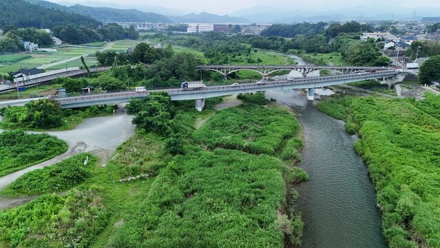 Aerial view of the Akigawa river flowing through lush green landscape with bridges and roads in Akiruno City, Tokyo, Japan.