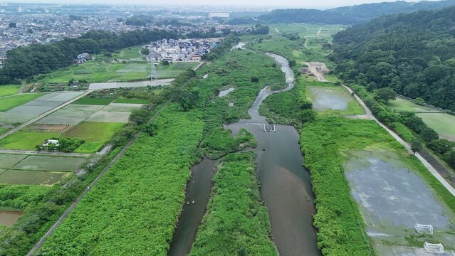 Aerial view of the Akigawa River flowing through lush green landscapes and agricultural fields in Tokyo, Tokyo, Japan.