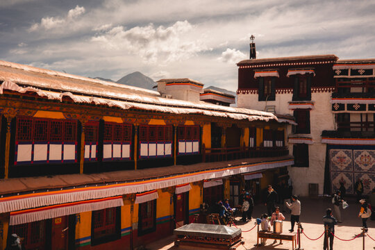 View of the historic Potala Palace courtyard with traditional Tibetan architecture, vibrant yellow and white walls, and visitors walking in Lhasa, Tibet, China.